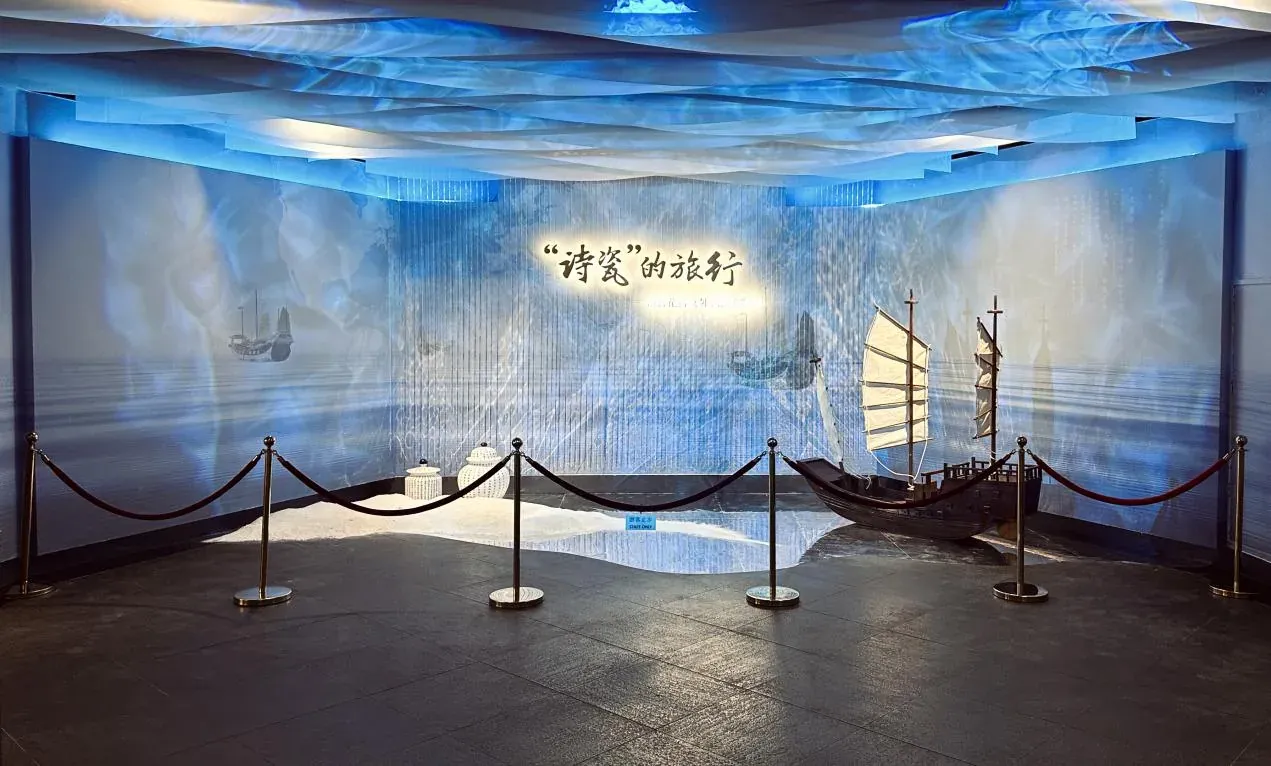 展厅入口的主题墙，蓝色灯光下是展览标题与一艘帆船模型，前方围着隔离带。
